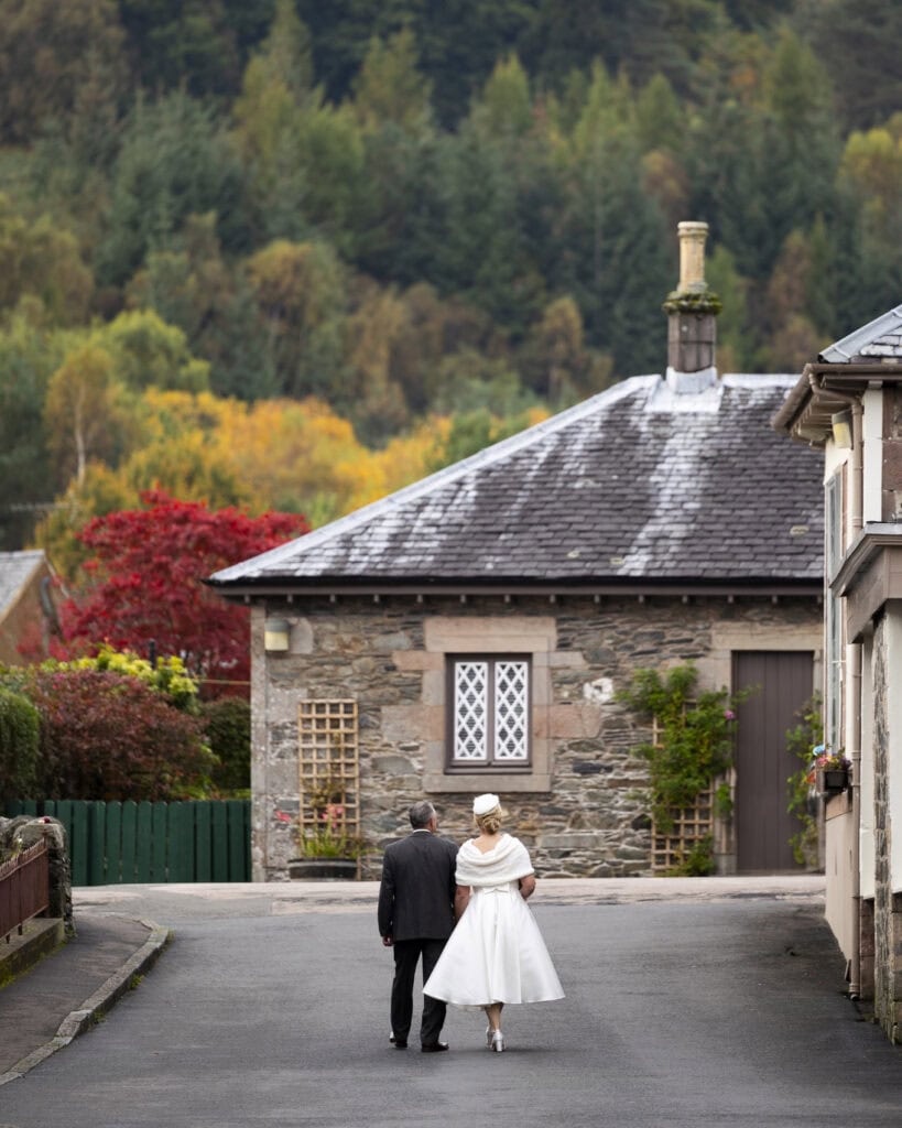 a just married couple walk through Luss village on loch lomond