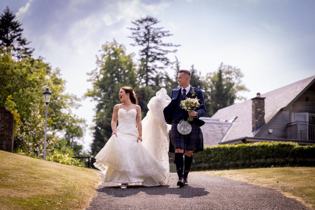 bride and groom laugh with guests walking towards loch lomond