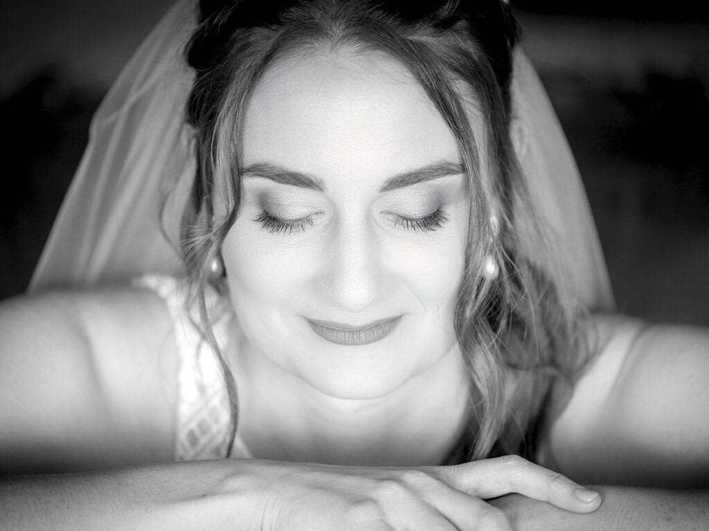 Bride in black and white portrait, eyes closed with a gentle smile and natural makeup