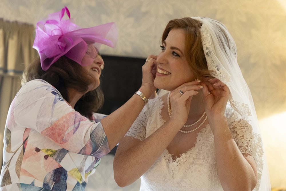 “Not everything needs to be filmed, filtered and posted — sometimes it’s enough just to be present.” Authentic beautiful moment where the brides mum helps bride get her earrings in