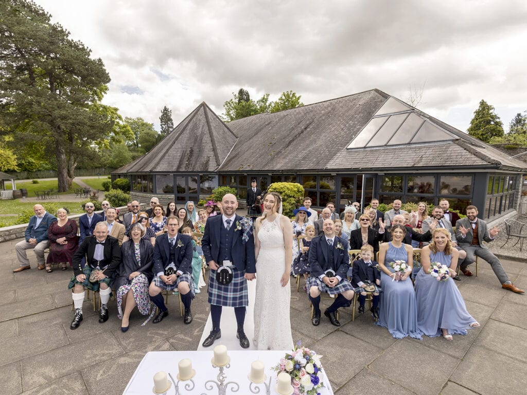 Bride and groom standing with guests outside The Cruin wedding venue on Loch Lomond