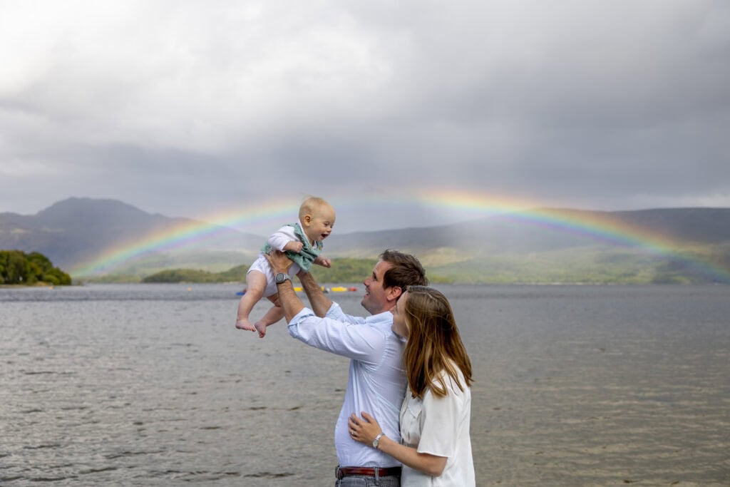 Family portrait, mum dad, baby with a rainbow on loch lomond