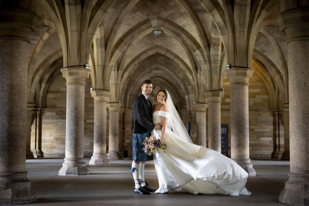 Bride and groom walking through Glasgow University cloisters