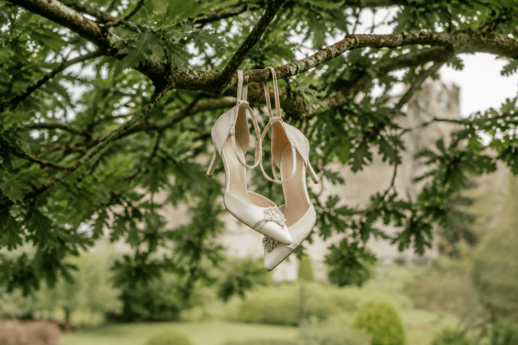 AI-generated satirical image of ivory wedding shoes hanging from a tree branch.